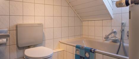 Un baño con inodoro, bañera y tragaluz.