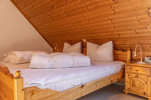 A wooden bunk bed with white bedding, a bedside table with a lamp, and a wooden nightstand. - Time unwind: The townhouse is located behind the dike and has for d (Harlesiel)