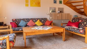 Una sala de estar acogedora con un conjunto de sofá, una mesa de centro de madera y una escalera.