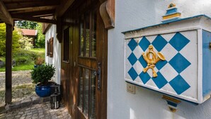A building with a wooden door and a blue and white diamond-patterned wall. - Farmhouse Tegernsee (Warngau)
