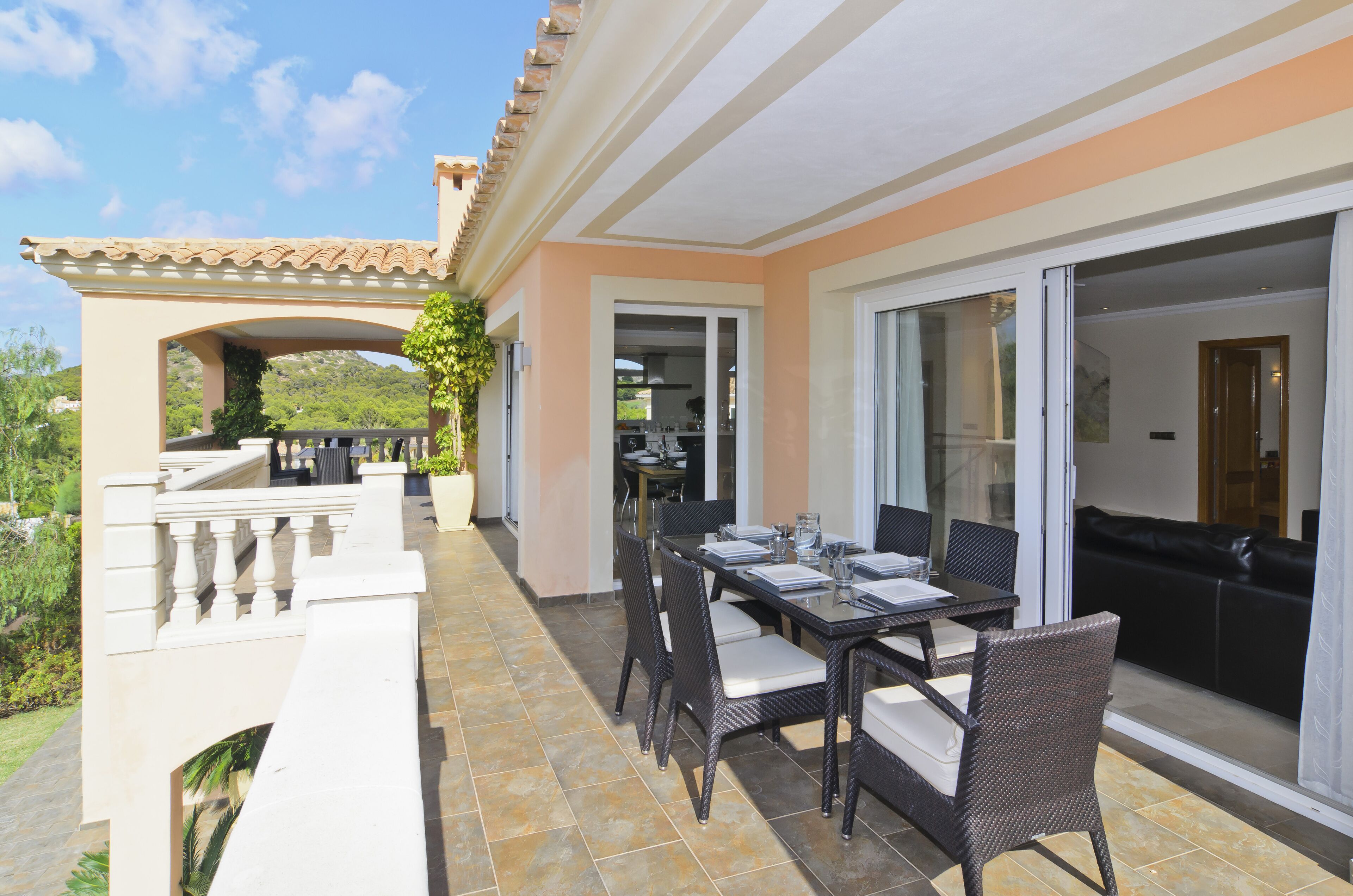 Une terrasse avec une table et des chaises, une porte-fenêtre coulissante et une vue sur le paysage.