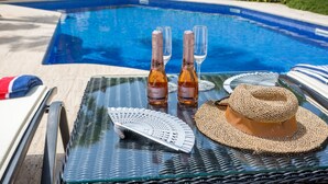 Una mesa de vidrio con dos botellas de Freixenet, un sombrero de paja y un abanico.