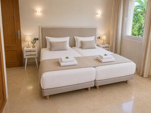 Un lit double avec deux oreillers, une table de chevet avec une lampe, une petite table de nuit avec une lampe et une fenêtre avec des rideaux.