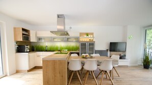 Una cocina moderna con una isla central, muebles blancos y un ventanal grande.