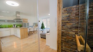 Una cocina moderna con armarios de madera, una zona de comedor con sillas y una sala de estar con sofá.