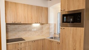 Une cuisine avec des meubles en bois, un four à micro-ondes en acier inoxydable et un dosseret carrelé.