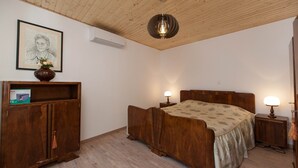 Une chambre à coucher avec un lit en bois, des lampes de chevet, une armoire en bois et un portrait encadré accroché au mur.