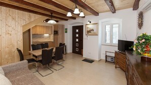 Un salon moderne comprenant un canapé, un coin repas avec des chaises, un téléviseur et un meuble en bois.