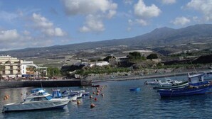 A coastal marina with boats docked, a mountainous backdrop, and buildings along the shore. - Playa San Juan, 2 room apartment close to the beach me WiFi (Playa San Juan)