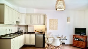 A modern kitchen with white cabinets, a built-in dishwasher, and a dining area with a white table and chairs. - Playa San Juan, 2 room apartment close to the beach me WiFi (Playa San Juan)