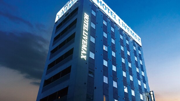 Ein Hochhaus-Hotel mit einem gut sichtbaren Schild, auf dem "HOTEL LIVINGMAX" steht.