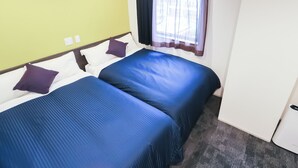 Ein Hotelzimmer mit zwei Betten, einem fensterbelaubten Fenster und einer grünen Wand.