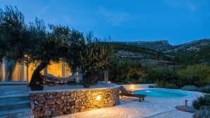 A stone pool surrounded by lounge chairs and a stone wall with a light fixture. - Private pool family home with open sea view (Bol)