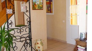 A staircase with a wrought iron railing, a hanging light fixture, and a small table with a clock. - Gite 37 bis rue du pré de la dame. (Férel)