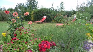 A garden with various flowers and a red lounge chair. - Gite 37 bis rue du pré de la dame. (Férel)