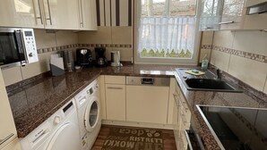 A compact kitchen with a washing machine, microwave, and a coffee maker. - Cozy cottage with much comfort (Rheinboellen)
