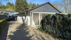 A single-story building with a covered porch, a brick pathway leading to the entrance, and a well-maintained hedge. - Cozy cottage with much comfort (Rheinboellen)