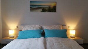 Un letto ben rifatto con biancheria a righe, due cuscini e due abat-jour su comodini.