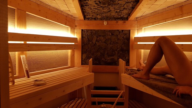 Una sauna con panche in legno e una parete in pietra.
