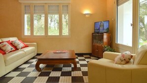 Un salon avec un sol à carreaux, un canapé, une table basse, un téléviseur et un meuble.