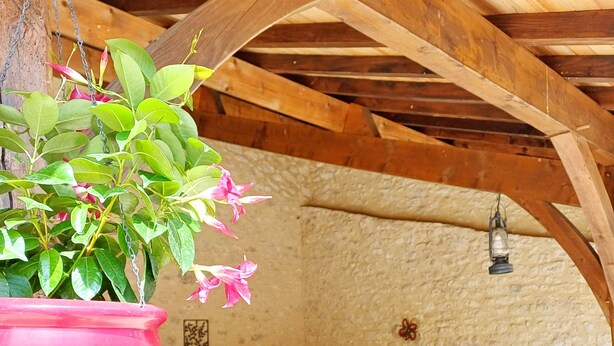 An outdoor seating area with a stone wall, wooden beams, and hanging plants. - Gite 8 people - forge - Monsegur (Monségur)