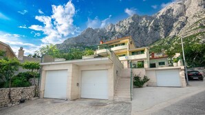 A two-story building with a balcony, a staircase, and two garage doors. - Villa Marino in Makarska, private pool (Makarska)