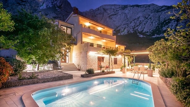 A two-story building with a swimming pool, surrounded by mountains and trees. - Villa Marino in Makarska, private pool (Makarska)