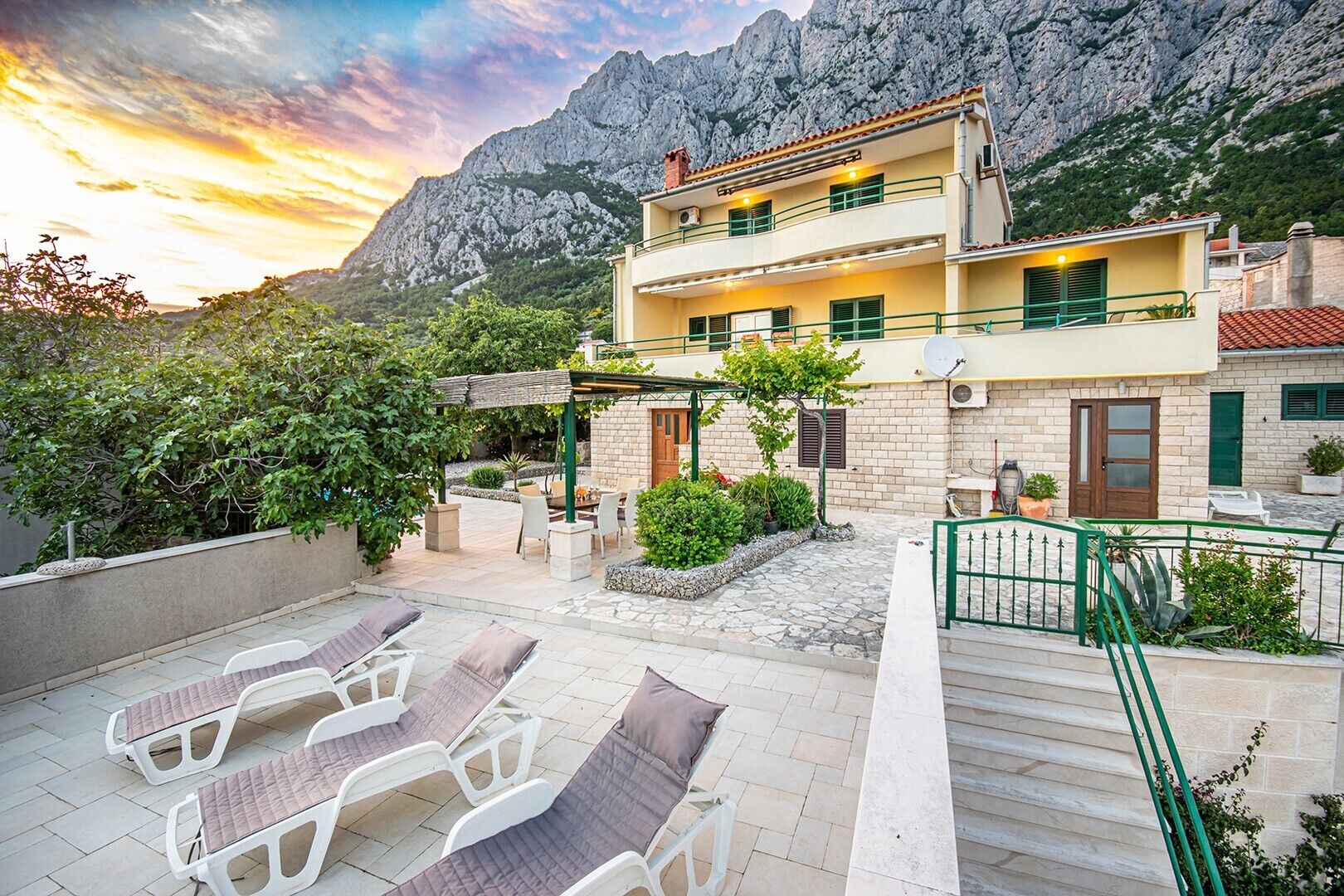 Un edificio de dos pisos con balcón, zona de estar al aire libre y vistas a las montañas.