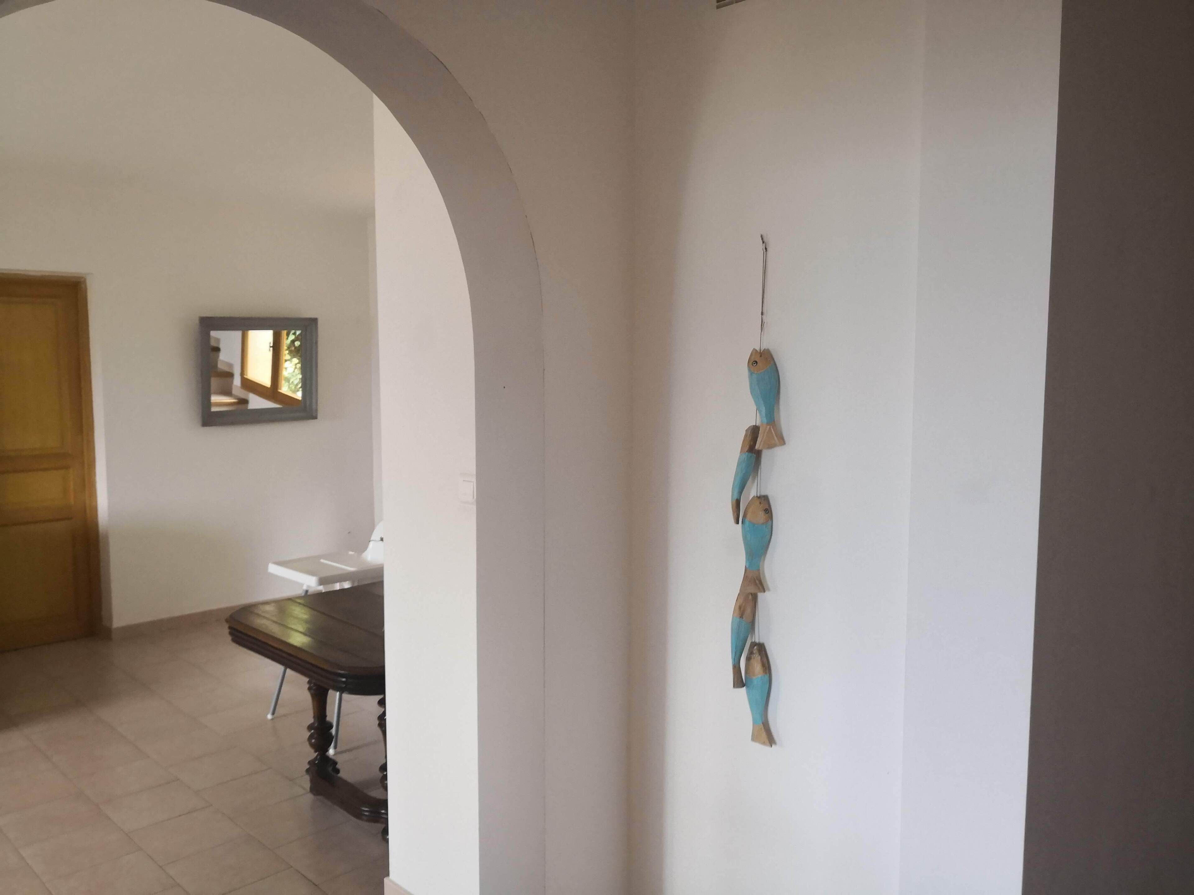 A hallway with a wooden door, a dining table, and a wall-mounted fish decoration.