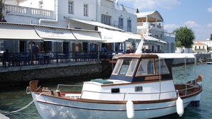 A small boat docked at a waterfront cafe with outdoor seating. - Villa KoKa - A small paradise near Ermioni (Petrothalassa Ermioni)