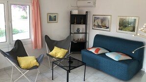 A living room with a blue sofa, two black chairs with yellow cushions, a glass coffee table, and artwork on the walls. - Villa KoKa - A small paradise near Ermioni (Petrothalassa Ermioni)