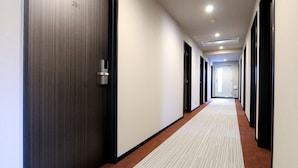 A corridor with doors on both sides, a carpeted floor, and a ceiling with recessed lighting. - HOTEL LiVEMAX Ueno-Ekimae (Tokyo)