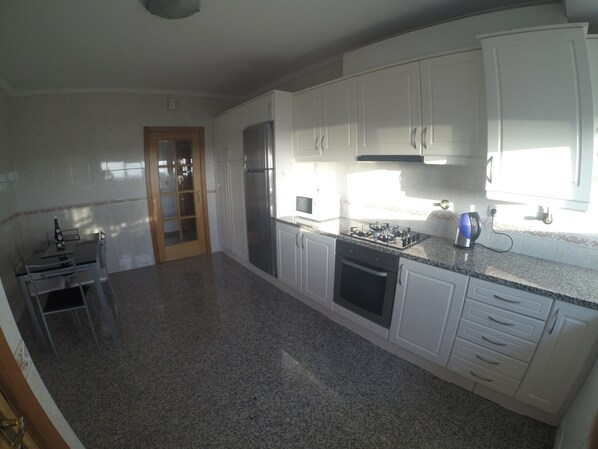 Una cocina con armarios blancos, horno empotrado y estufa a gas.