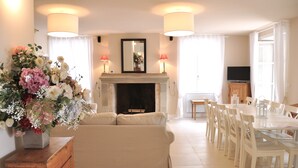 Ein Wohnzimmer mit Kamin, einer Couch, einem Esstisch und Stühlen.