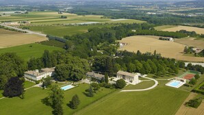 Eine Luftaufnahme eines weitläufigen Anwesens mit mehreren Gebäuden, einem Schwimmbad und ausgedehnten Grünflächen.