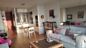 A modern living room with a sofa, a coffee table, and a dining area with a table and chairs.