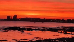 A sunset over a body of water with a city skyline in the background.