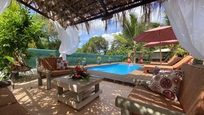 A poolside area with a wooden deck, lounge chairs, and a table with a floral centerpiece.