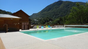 Piscina com um prédio de madeira e montanhas ao fundo.