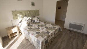 A bedroom with a bed, a nightstand, a radiator, and a door leading to another room.