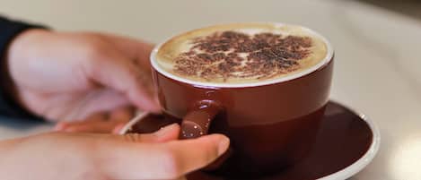 Eine Kaffeetasse mit schaumiger Milch auf einem Untertasse.