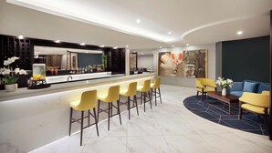 A modern hotel lobby with a bar area, yellow bar stools, a blue sofa, and a coffee table. - Swiss-Belhotel Napier (Napier)