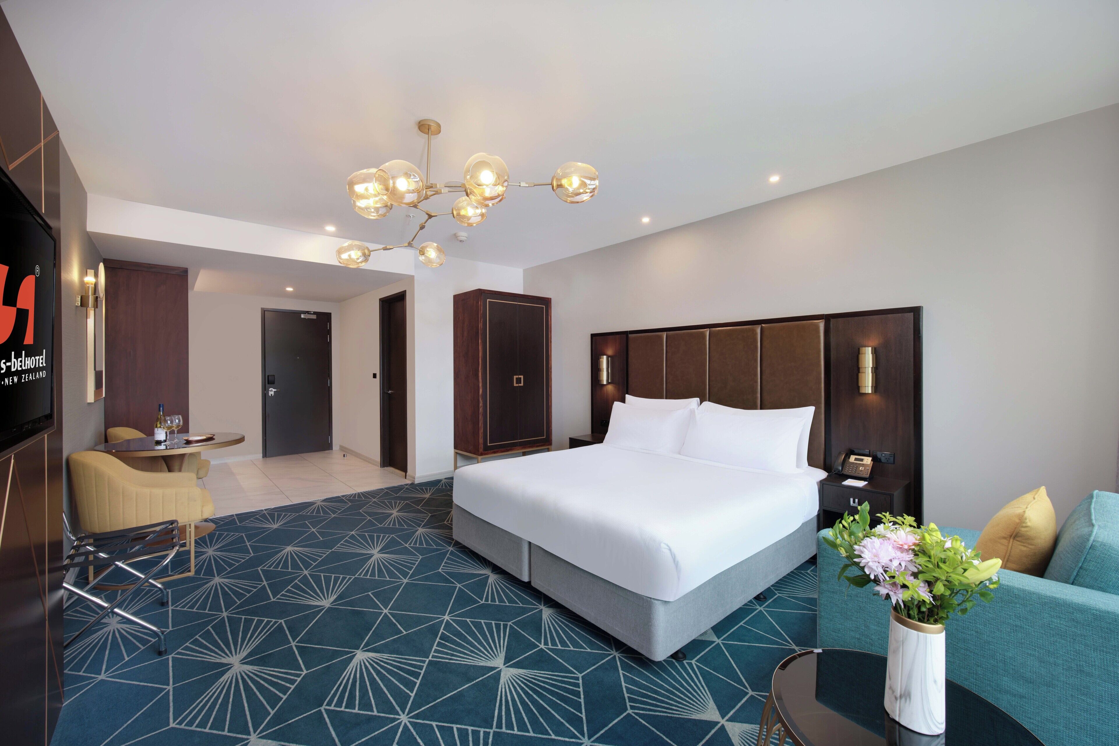 Una habitación de hotel moderna con una cama grande, un sofá, una mesa de comedor y un televisor.