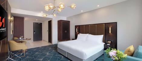 Una habitación de hotel moderna con una cama grande, un sofá, una mesa de comedor y un televisor.