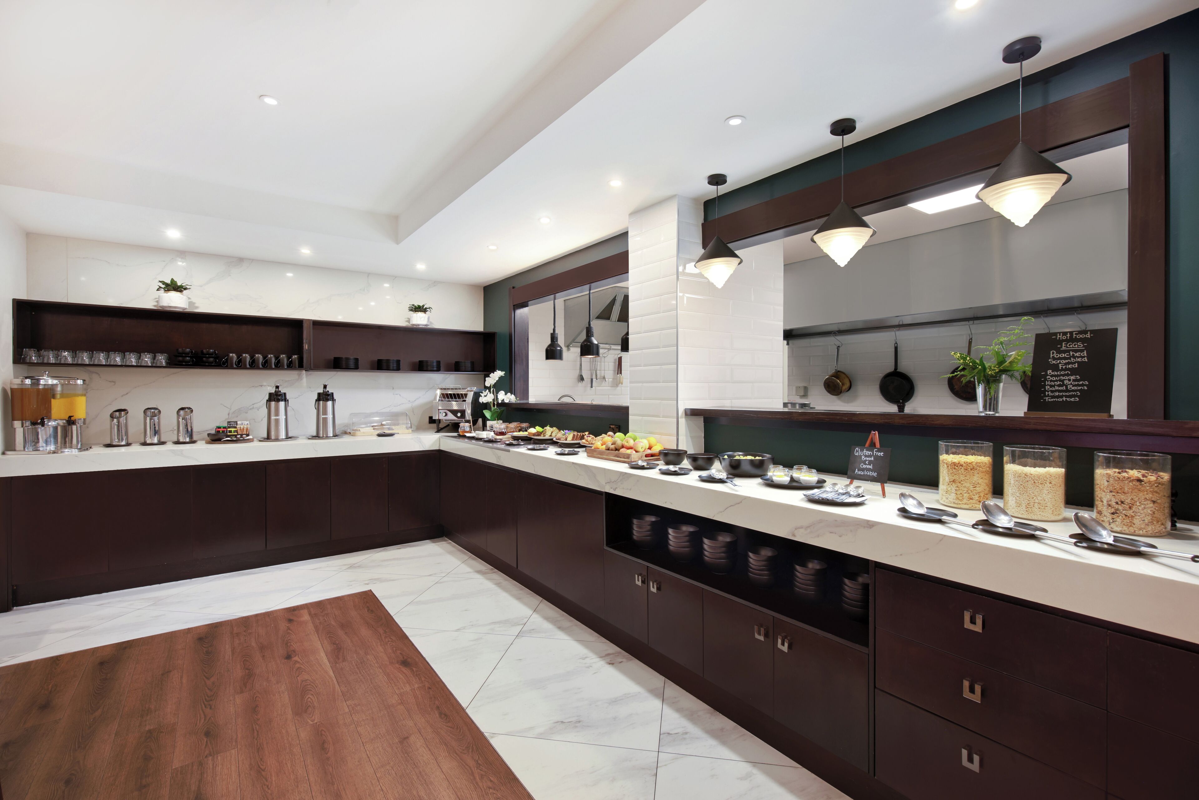Una cocina moderna con encimera de mármol, armarios oscuros e iluminación colgante.
