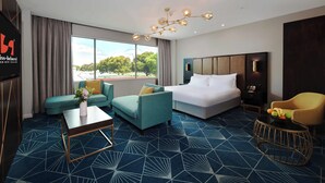 A hotel room with a large bed, a sofa, a chair, a coffee table, and a TV. - Swiss-Belhotel Napier (Napier)