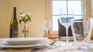 A dining table set with plates, cutlery, and wine glasses, a bottle of wine, and a vase with flowers. - Apartment at Landhof Rothenberg - terrace with views of meadows and forests (Rothenberg)
