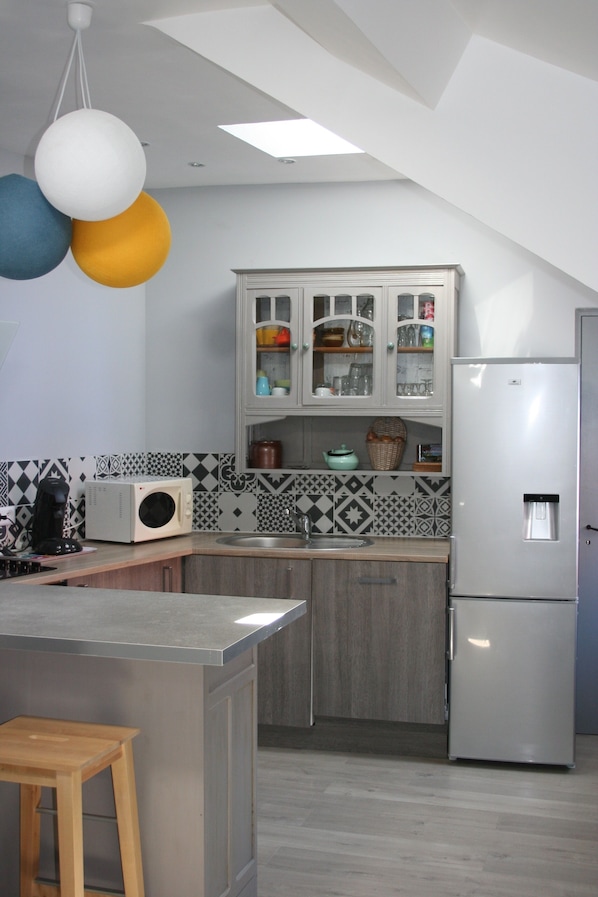 A modern kitchen with a central island, a built-in microwave, a refrigerator, and a sink.