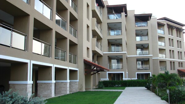 A multi-story building with balconies, a central courtyard, and a pathway leading to the entrance.