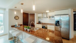 Eine moderne Küche mit Granit-Arbeitsplatten, Edelstahlgeräten und Pendelleuchten.